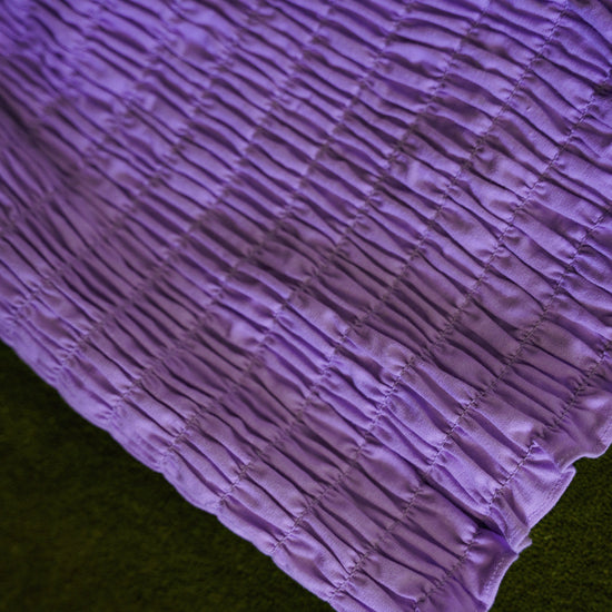 Close-up of purple cotton bloomers showing all-over elastic smocking and softly ruffled leg openings.